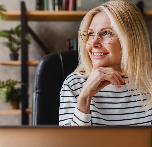 happy-senior-woman-holding-pen-daydreaming-looking-away-sitting-front-workplace